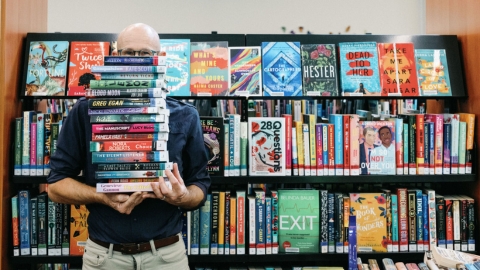 man in library holding books